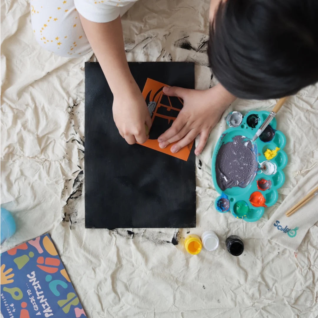 A child painting on a black canvas with Sculpd kids canvas kit
