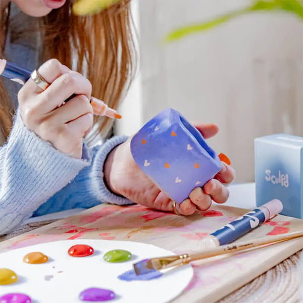 A woman colouring her sculpted candle with Sculpd paint pens